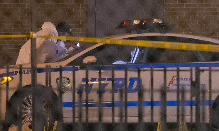 Investigators work at the scene where two NYPD officers were shot, Saturday, Dec. 20, 2014 in the Bedford-Stuyvesant neighborhood of the Brooklyn borough of New York. Police said an armed man walked up to two officers sitting inside the patrol car and opened fire before running into a nearby subway station and committing suicide. Both police officers were killed. (AP Photo/John Minchillo)