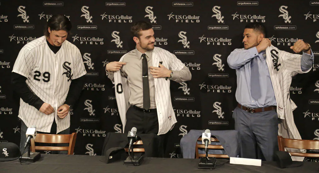 (L-R) Pitchers Jeff Samardzija and David Robertson and free-agent outfielder Melky Cabrera don their baseball jerseys while being introduced as the newest Chicago White Sox at a news conference in Chicago on Dec. 16, 2014. It is not just Sox baseball fans who are thinking big this year. So are the Cubs. North Side and South Side, there is a big baseball buzz in Chicago. (AP Photo/M. Spencer Green)