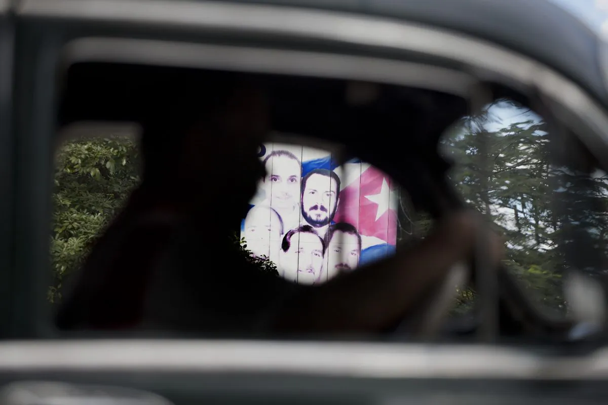 A billboard showing "The Cuban Five" is seen through the other side of an American classic car driving through Havana, Cuba, Wednesday, Dec. 17, 2014. The Cuban Five were part of the "Wasp Network" sent by then-Cuban President Fidel Castro to spy in South Florida. The men, who are hailed as heroes in Cuba, were convicted in 2001 in Miami on charges including conspiracy and failure to register as foreign agents in the U.S. On Wednesday, Dec. 17, 2014, three of the five Cubans were released by the U.S. in exchange for U.S. citizen Alan Gross and an unnamed Cuban man who was imprisoned for nearly 20 years for spying for the United States. Two of the Cuban Five had previously been released after finishing their sentences. (AP Photo/Desmond Boylan)