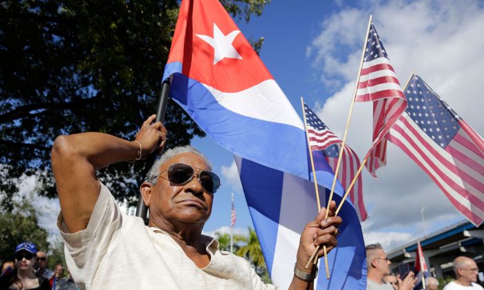 Evilio Ordonez holds Cuban and American flags during a protest against President Barack Obama's plan to normalize relations with Cuba, in the Little Havana neighborhood of Miami, Fla., on Dec. 20, 2014. (AP Photo/Lynne Sladky)