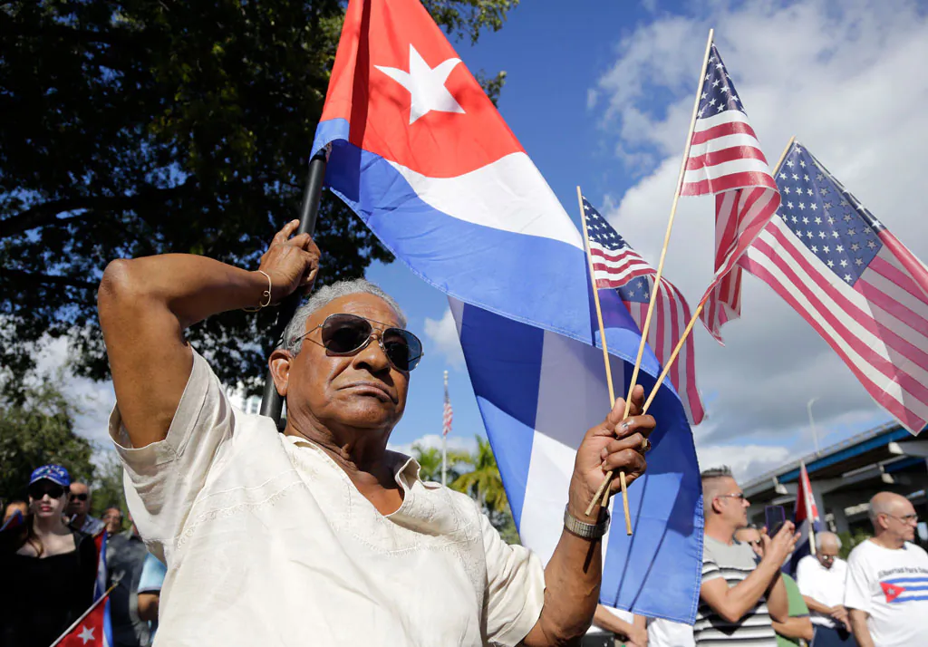 Evilio Ordonez holds Cuban and American flags during a protest against President Barack Obama's plan to normalize relations with Cuba, in the Little Havana neighborhood of Miami, Fla., on Dec. 20, 2014. (AP Photo/Lynne Sladky)