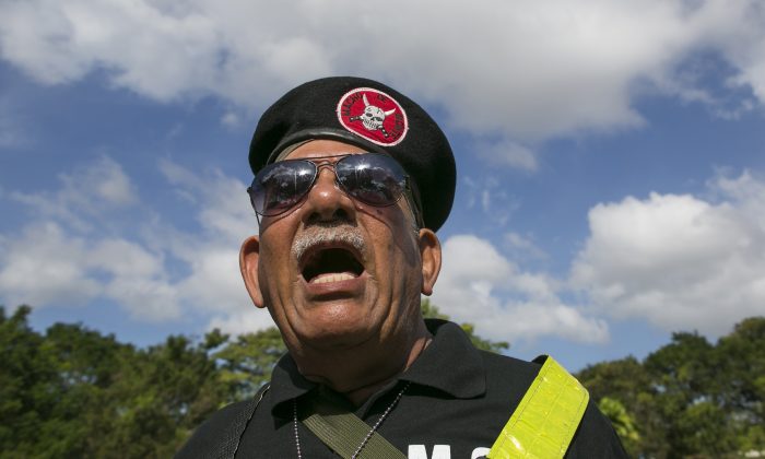 Vidal Martinez, former member of the Macho de Monte Division of the Panamanian Defense Forces, sings his national anthem during a ceremony in tribute to the victims of the U.S. invasion at a cemetery in Panama City, Saturday, Dec. 20, 2014. The U.S. intervention known as Just Cause began 25 years ago on Saturday, on Dec. 20, 1989, and ended with Noriega’s surrender to American drug agents on Jan. 3. The invasion killed 314 Panamanian soldiers and 200 civilians, the government says, while the U.S. military reported losing 23 American soldiers. Local human rights organizations estimated that more than 1,000 Panamanians died. (AP Photo/Tito Herrera)