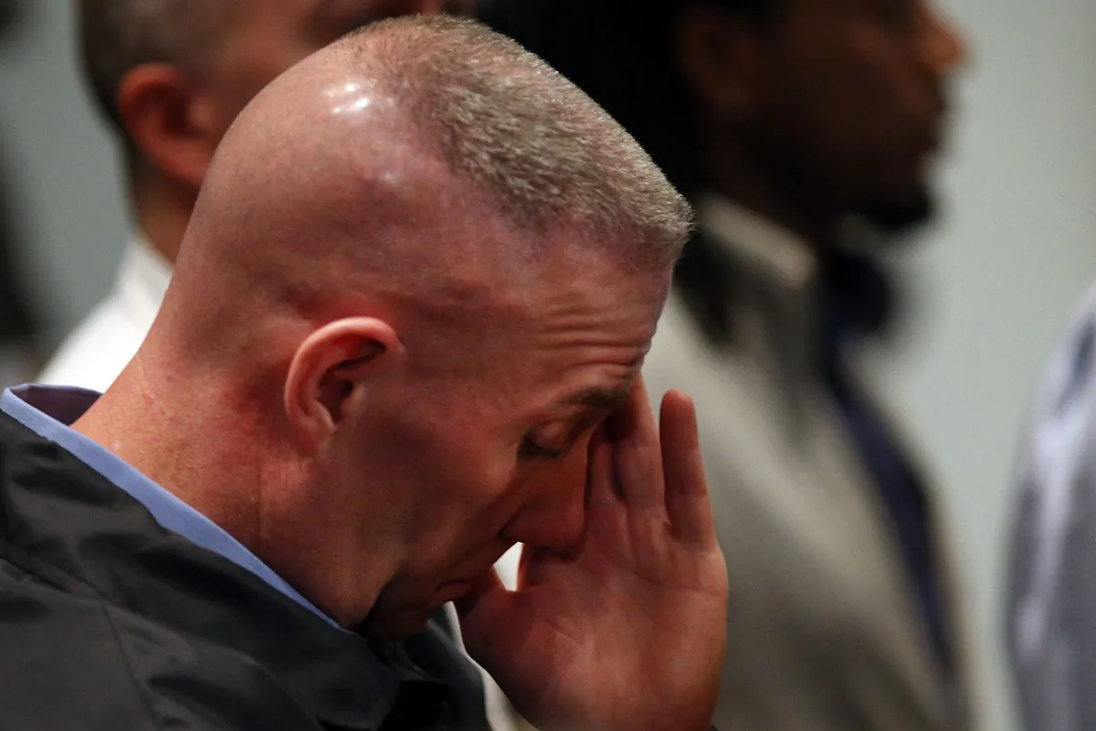 A police officer pauses as he listens to New York City Police Commissioner William J. Bratton and Mayor Bill de Blasio at a news conference at Woodhull Hospital following the killing of two New York City police officers on Dec. 20, 2014. (Spencer Platt/Getty Images)