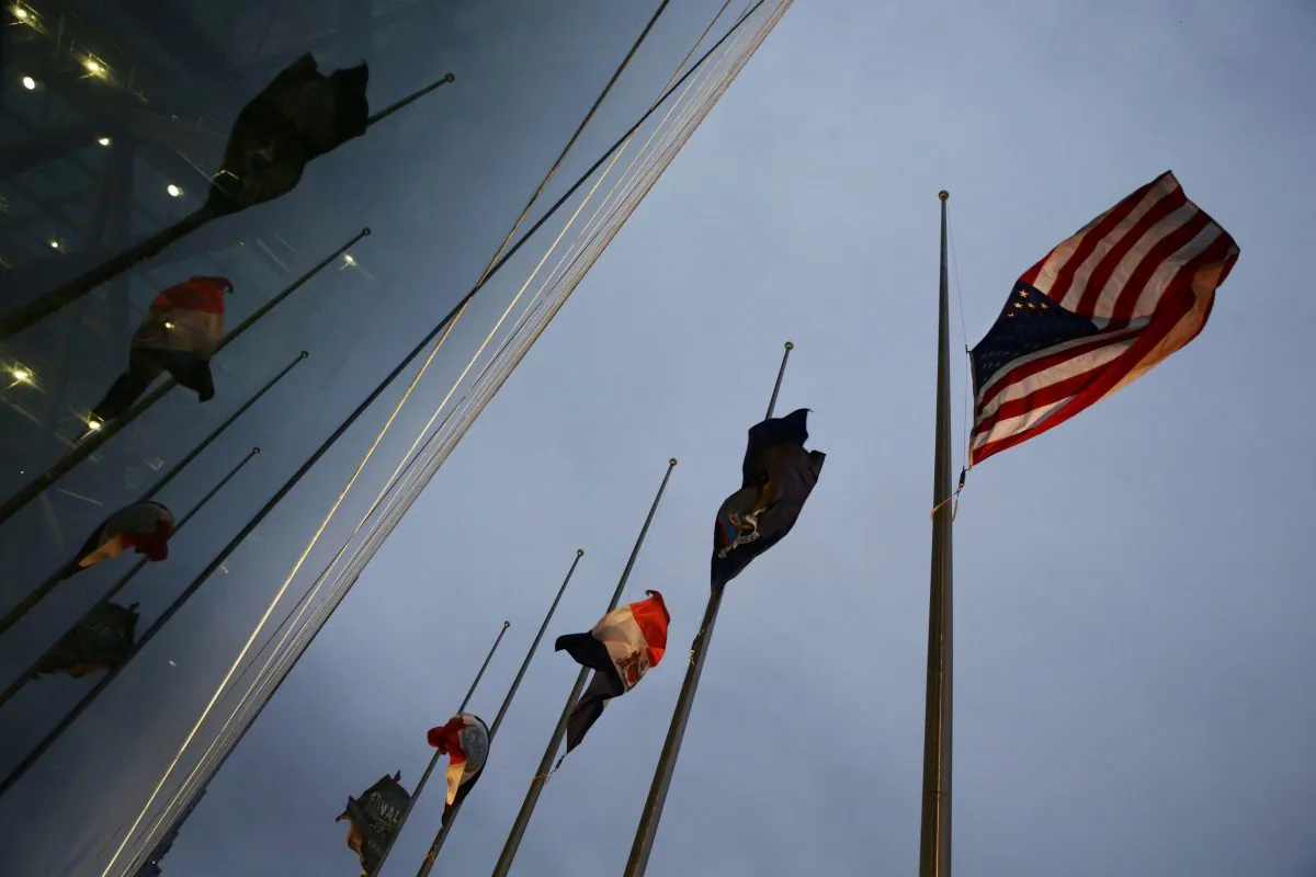 The American and New York state and city flags fly at half-staff outside the Jacob K. Javits Convention Center in New York on Sunday, Dec. 21, 2014. The flags were lowered in observance of the deaths of New York Police Department officers Rafael Ramos and Wenjian Liu who were slain on Saturday. (AP Photo/Peter Morgan)