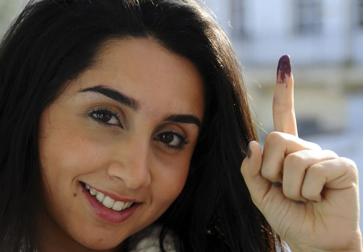 Tunisian voter Dina Ghlisse, 19, displays her finger with the indelible ink mark after voting in La Marsa, on the outskirts of Tunis, Tunisia, Sunday, Dec. 21, 2014. Tunisians must decide Sunday between Beji Caid Essebsi, an 88-year-old veteran of previous regimes, and Moncef Marzouki, a 75-year-old human rights activist who is the outgoing interim president. For the third time in just two months, Tunisian voters will head to the polls this weekend, this time to elect a president in a runoff vote that presents a stark choice between the country's past and its Arab Spring revolution. (AP Photo/Hassene Dridi)