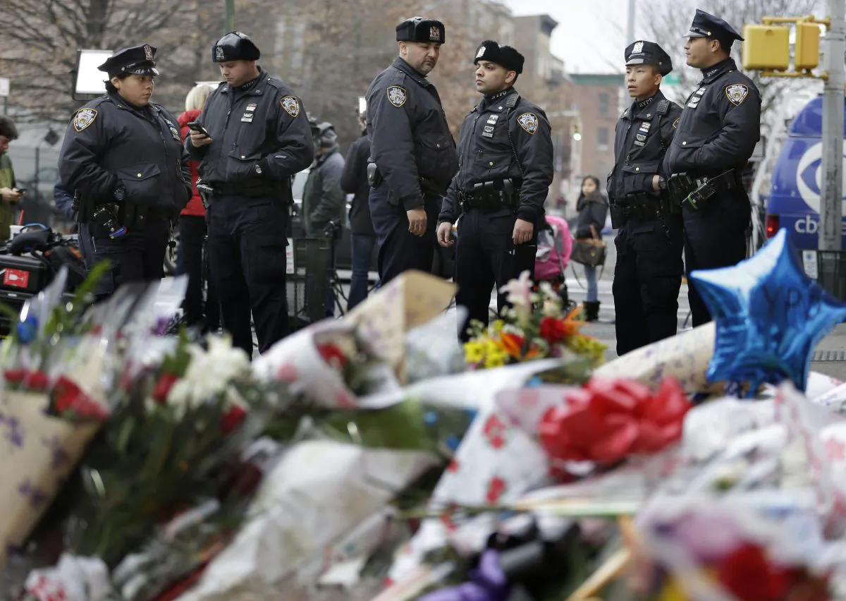 New York City police officers gather near a makeshift memorial on Monday, Dec. 22, 2014, near the site where fellow officers Rafael Ramos and Wenjian Liu were murdered in the Brooklyn borough of New York. (AP Photo/Seth Wenig)