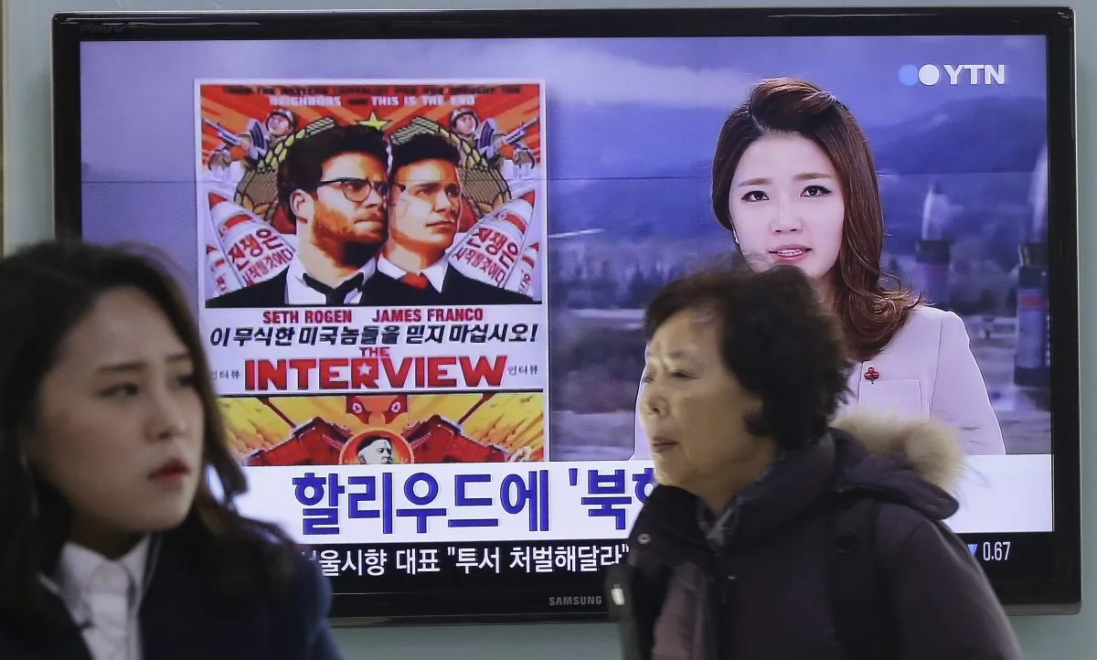 People walk past a TV screen showing a poster of Sony Picture's "The Interview" in a news report, at the Seoul Railway Station in Seoul, South Korea, Monday, Dec. 22, 2014. North Korea hates the Hollywood film that revolves around the assassination of its beloved leader, but the country has had a long love affair with cinema - of its own particular styling. The Korean letters on the screen read "Hollywood." (AP Photo/Ahn Young-joon)