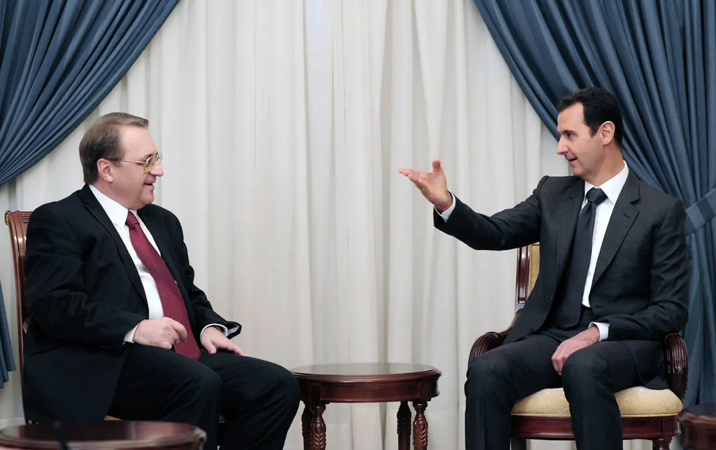 Syrian President Bashar Assad (R) speaks with Russia's deputy Foreign Minister Mikhail Bogdanov in Damascus, Syria, on Dec. 10, 2014. The search for a negotiated settlement to the Syrian civil war is gaining steam, as Assad’s forces feel increasingly squeezed on the battlefield and Islamic extremist groups proliferate across the region. (AP Photo/SANA)