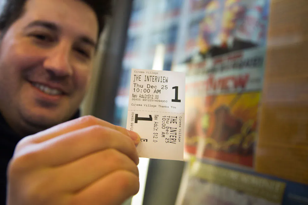 Derek Karpel holds his ticket to a screening of "The Interview" at Cinema Village movie theater in Manhattan, N.Y., on Thursday, Dec. 25, 2014. Sony canceled the film's Christmas Day release after threats of violence by hackers linked to North Korea, but the release was reinstated in some independent theaters. (AP Photo/John Minchillo)