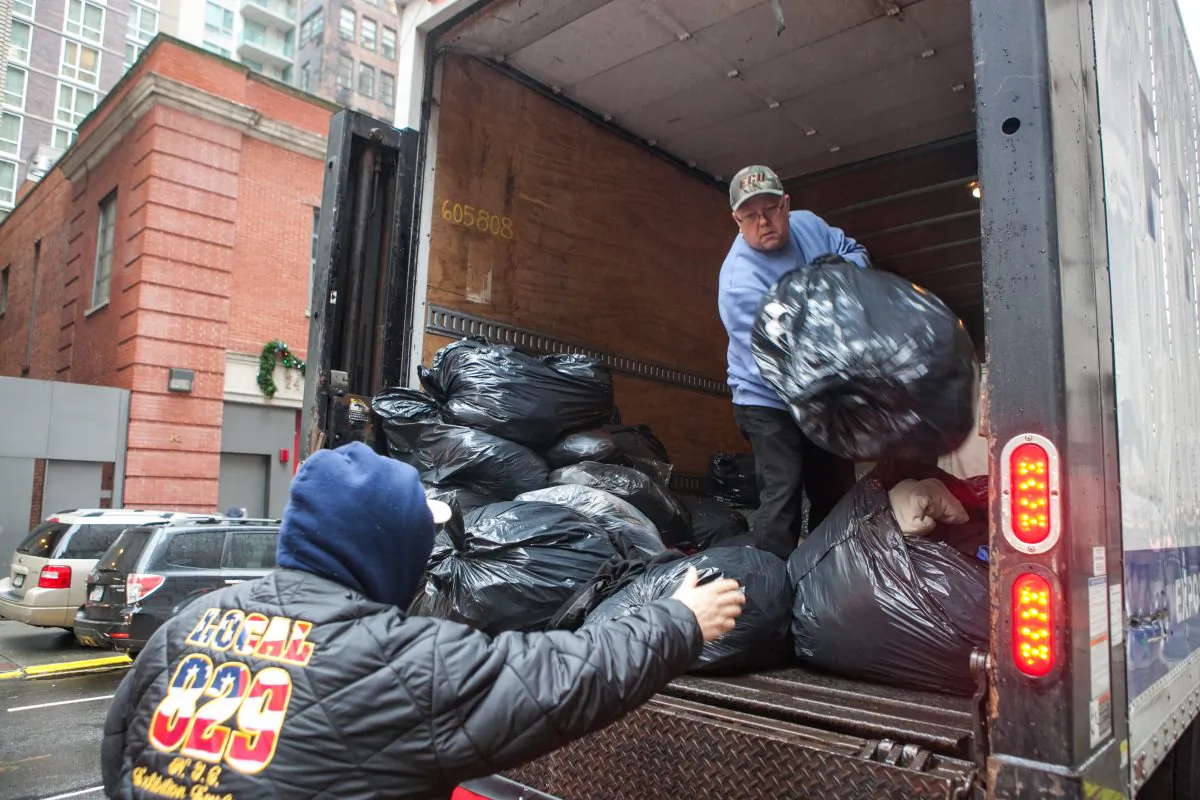Volunteers from New York Cares unload over 3,000 bags of coats in New York on Dec. 23, that were donated by car dealerships and will be given to those in need. (Benjamin Chasteen/Epoch Times