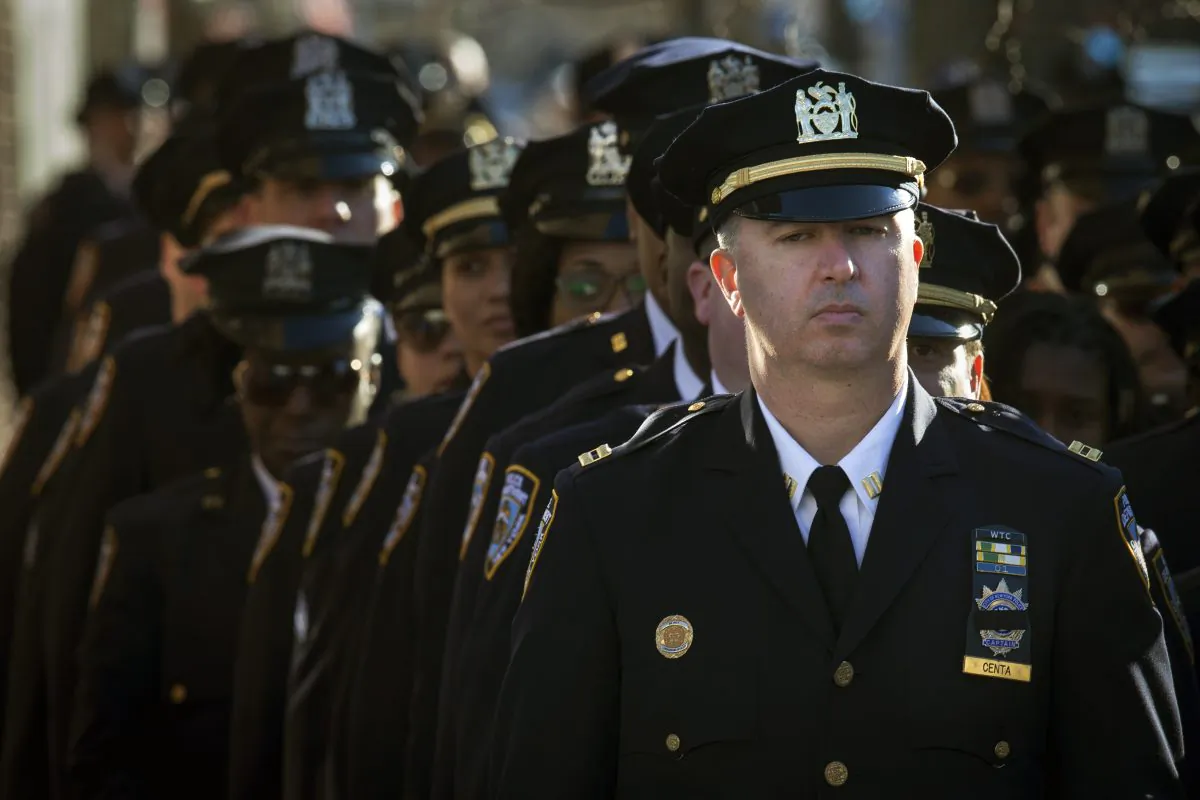 New York Police Department officers wait in line to enter the wake of officer Rafael Ramos at Christ Tabernacle Church, in the Glendale section of Queens, Friday, Dec. 26, 2014, in New York. Ramos was killed Dec. 20 along with his partner, Officer Wenjian Liu, as they sat in their patrol car on a Brooklyn street. The shooter, Ismaaiyl Brinsley, later killed himself. (AP Photo/John Minchillo)