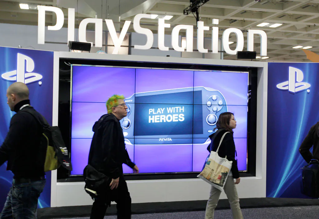 Attendees walking past the Sony PlayStation PS Vita console on display in the Sony PlayStation booth at the Game Developers Conference in San Francisco on March 8, 2012. (AP Photo/Paul Sakuma)