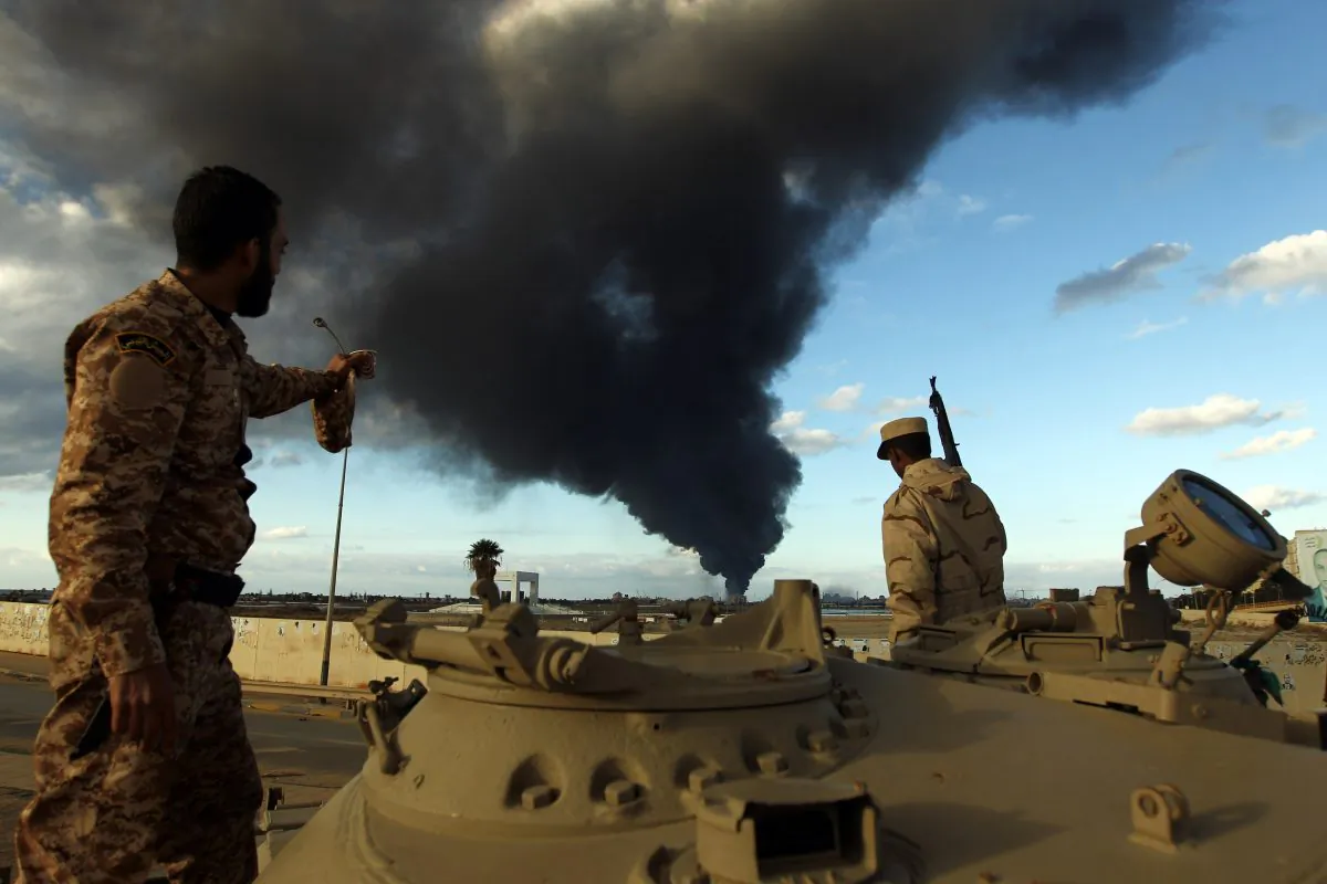 Members of the Libyan army stand on a tank as heavy black smoke rises from the city's port in the background after a fire broke out at a car tyre disposal plant during clashes against Islamist gunmen in the eastern Libyan city of Benghazi on Dec. 23, 2014. Forces loyal to former general Khalifa Haftar and to internationally recognised Prime Minister Abdullah al-Thani have been battling for weeks against Islamists who have taken control of much of Libya's second city, and the capital Tripoli. (Abdullah Doma/AFP/Getty Images)