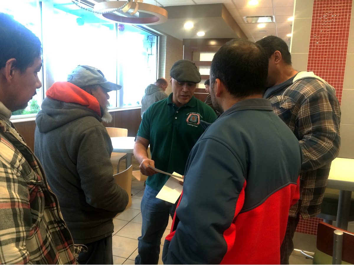 Manny Gines (2nd R), organizer for the New England Regional Council of Carpenters, speaks with three carpenters who recently received overdue wages after filing a complaint with the Attorney General’s office, at a McDonald’s in Boston, Mass., on Dec. 19, 2014. (Phoebe Ryles/Epoch Times)