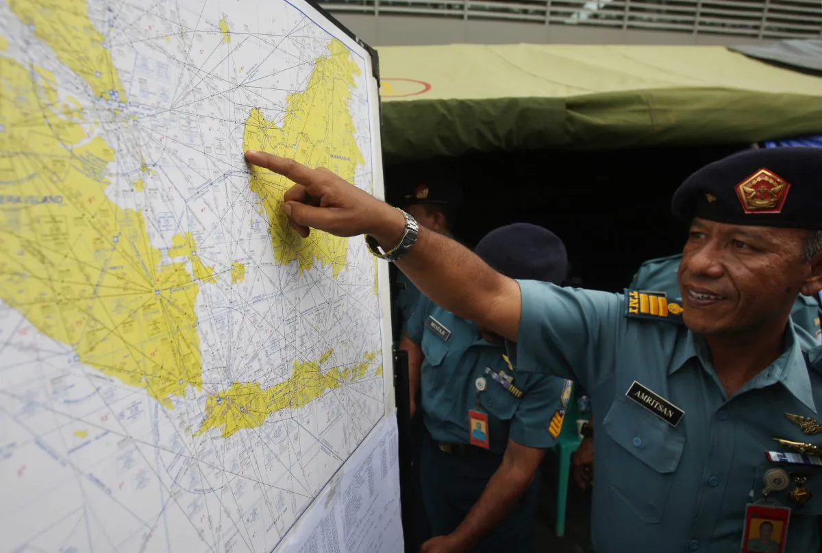 A military personnel points to a map of Indonesia at the crisis center set up by local authorities in search of the missing AirAsia flight QZ8501 at Juanda International Airport in Surabaya, East Java, Indonesia, Monday, Dec. 29, 2014. Search planes and ships from several countries on Monday were scouring Indonesian waters over which an AirAsia jet disappeared, more than a day into the region's latest aviation mystery. AirAsia Flight 8501 vanished Sunday in airspace thick with storm clouds on its way from Surabaya, Indonesia, to Singapore. (AP Photo/Trisnadi Marjan)