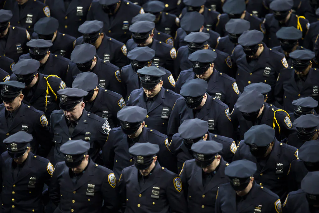 New recruits bow their heads in honor of deceased officers Rafael Ramos and Wenjian Liu during a New York Police Academy graduation ceremony, Monday, Dec. 29, 2014, at Madison Square Garden in New York. Nearly 1000 officers were sworn in as tensions between city hall and the NYPD continued following the Dec. 20 shooting deaths of officers Ramos and Liu. (AP Photo/John Minchillo)