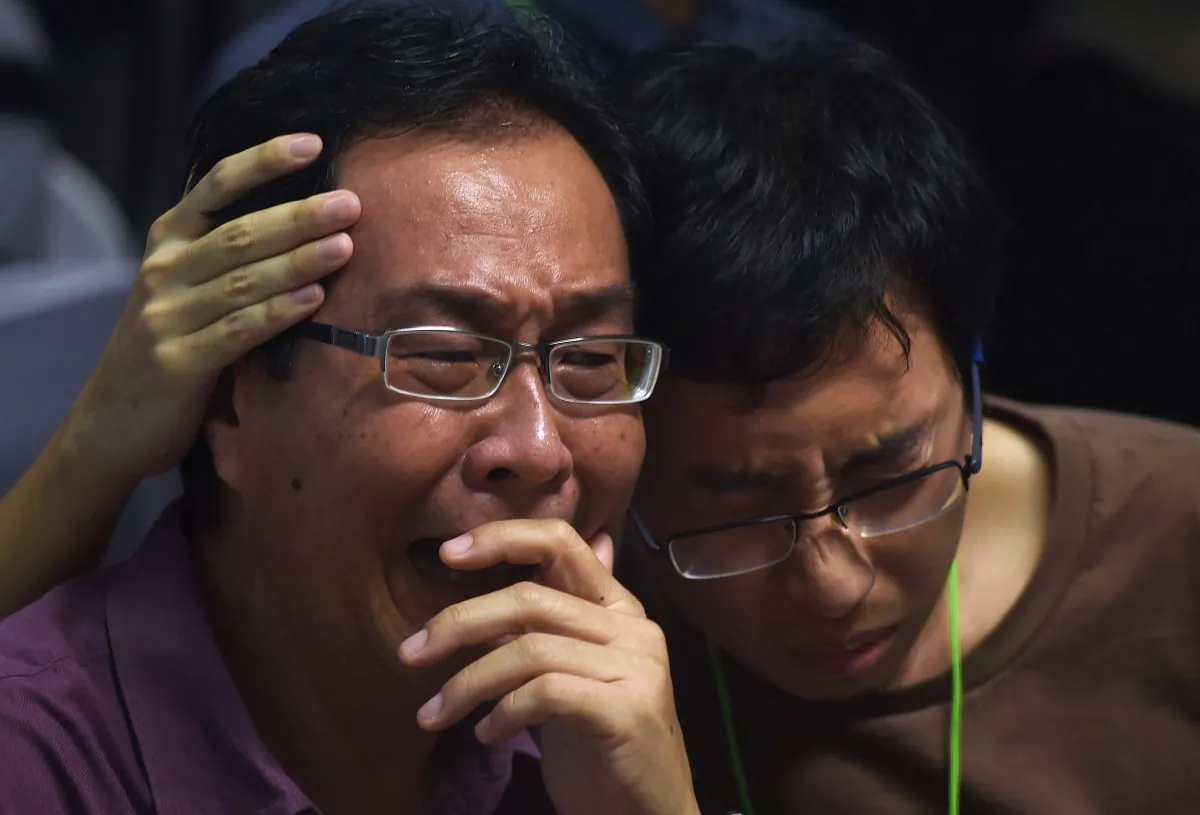Family members of passengers onboard the missing Malaysian air carrier AirAsia flight QZ8501 react after watching news reports showing an unidentified body floating in the Java sea, inside the crisis-centre set up at Juanda International Airport in Surabaya on Dec. 30, 2014. (Manan Vatsyayana/AFP/Getty Images)