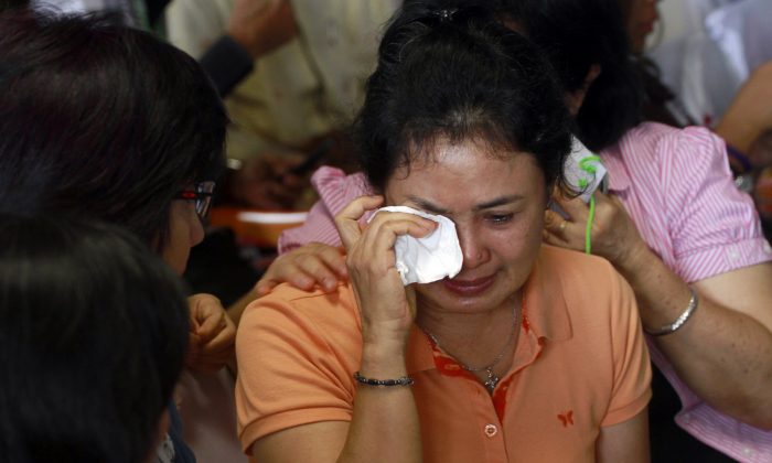 A relative of passengers of the missing AirAsia flight QZ8501 weeps as they wait at the crisis center at Juanda International Airport in Surabaya, East Java, Indonesia, Tuesday, Dec. 30, 2014. Several pieces of debris have been spotted floating in the sea off Borneo island, possibly linked to the missing AirAsia jetliner, an Indonesia National Search and Rescue spokesman said Tuesday.(AP Photo/Firdia Lisnawati)