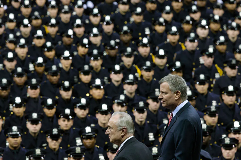 NYC Mayor Bill de Blasio (R) and NYPD police commissioner Bill Bratton (C) stand on stage during a New York Police Academy graduation ceremony, Monday, Dec. 29, 2014, at Madison Square Garden in New York. Nearly 1000 officers were sworn in as tensions between city hall and the NYPD continued following the Dec. 20 shooting deaths of officers Rafael Ramos and Wenjian Liu. (AP Photo/John Minchillo)
