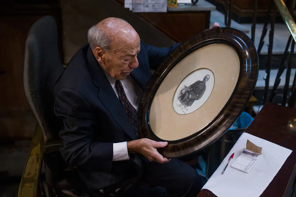 Angel Garcia, 89, looks at a picture of former King of Spain, Alfonso XIII with his autograph, as he collects belongings during the shutdown of his store called "Hernando" after 57 years running in Madrid, Spain, on Dec. 29, 2014. About 200,000 mostly family-owned stores, bars and restaurants are affected by the law change that allows their landlords to raise rents to whatever they want. An estimated 55,000 businesses are expected to close down over the coming weeks and months, wiping out around 120,000 jobs in a country which already has a 24 percent unemployment rate, labor groups say. Supporters of the current lease holders say Spain will lose part of its cultural identity as international chain franchises take over the spaces. (AP Photo/Andres Kudacki)