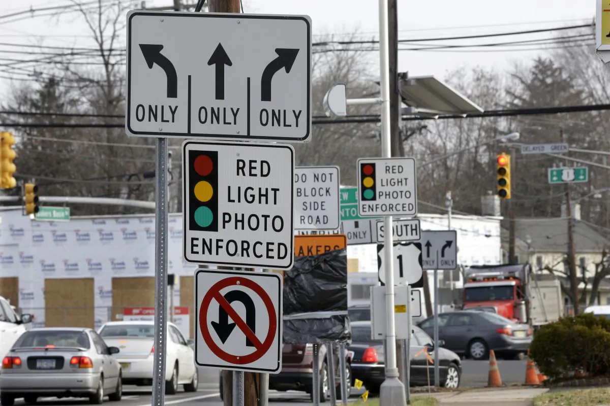 Traffic passes a red-light photo enforcement sign below a red-light camera in Lawrence Township, N.J., on Dec. 16, 2014. New Jersey legislators recently discontinued the state’s red-light camera pilot program after five years. (AP Photo/Mel Evans)