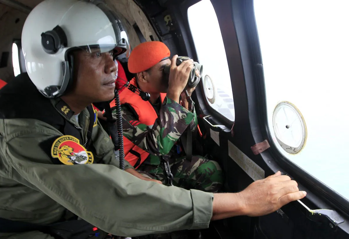 Crew members of Indonesian Air Force NAS 332 Super Puma helicopter look out of the windows during a search operation for the victims of AirAsia Flight 8501 over Kumai Bay, Indonesia, Friday, Jan. 2, 2015. (AP Photo/Bagus Indahono, Pool)