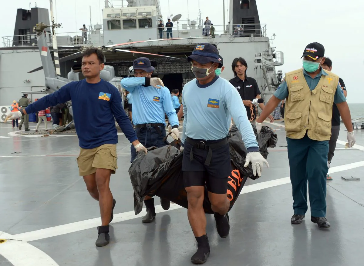 Indonesian's Navy personnel carry a bag containing a dead body of a passenger of AirAsia Flight 8501 at sea off the coast of Pangkalan Bun, Indonesia, Saturday, Jan. 3, 2015. Indonesian officials were hopeful Saturday they were honing in on the wreckage of AirAsia Flight 8501 after sonar equipment detected two large objects on the ocean floor, a full week after the plane went down in stormy weather. (AP Photo/Adek Berry, Pool)