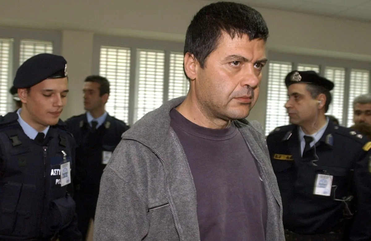Christodoulos Xiros is escorted by police officers as he enters a courtroom at Athens' Korydallos maximum security prison on March 6, 2003. Greek police have announced they arrested convicted terrorist Christodoulos Xiros early Saturday Jan. 3, 2014, who had failed to return to prison while on a furlough almost a year ago. The 56-year-old Xiros was serving six life terms for his part as a member of terrorist group November 17, which killed 23 people, including Greek politicians, businessmen and British, American and Turkish diplomats and military officials, from 1975 to 2000. (AP Photo/Aris Messinis)