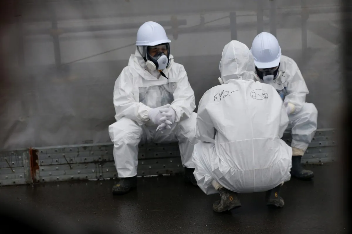 Workers wearing protective gear rest on a road at the Fukushima Dai-ichi nuclear power plant in Okuma, Fukushima Prefecture, northeastern Japan on Nov. 12, 2014. (Shizuo Kambayashi/AFP/Getty Images)
