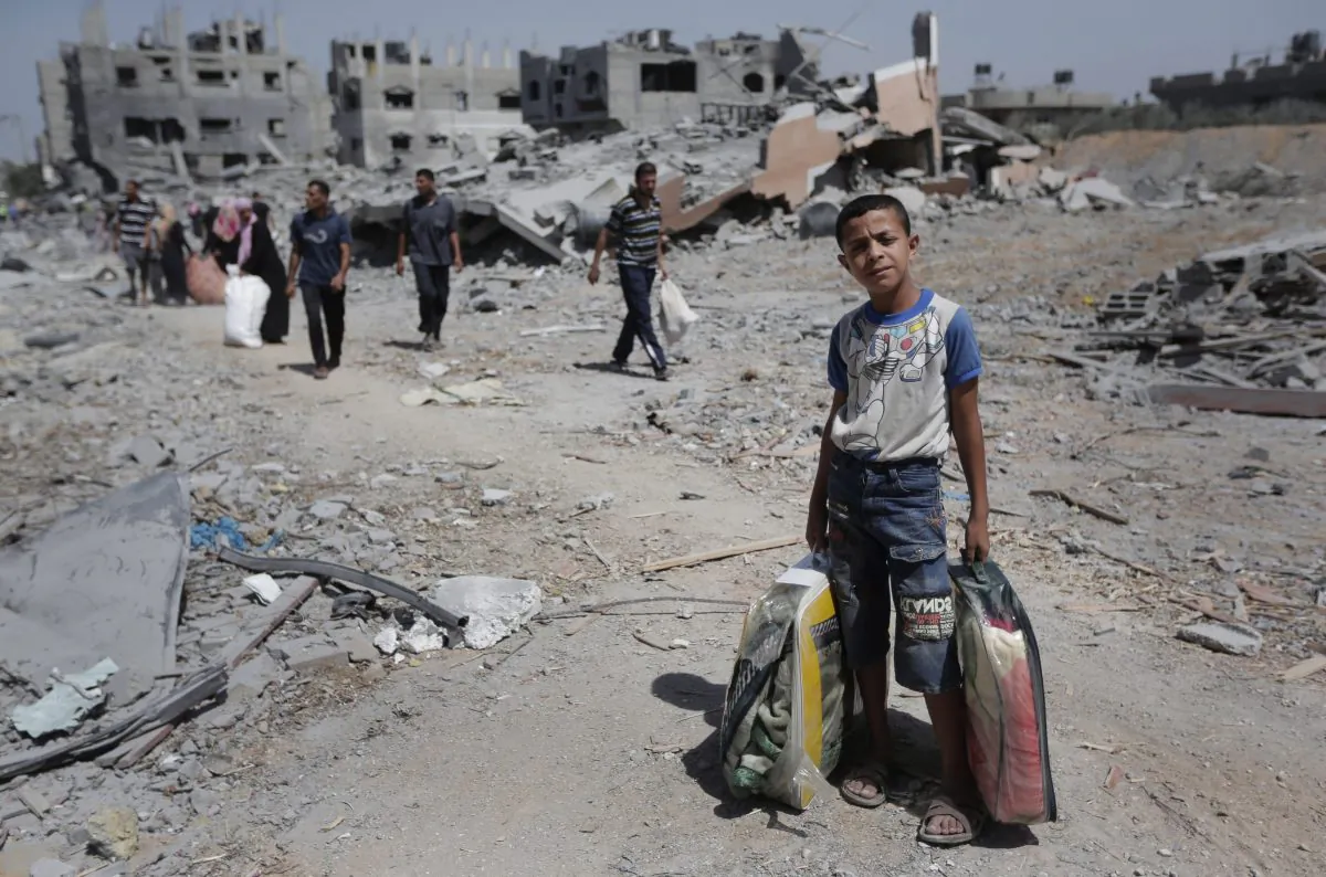 In this Aug. 1, 2014 file photo, Palestinians carry their belongings after salvaging them from their destroyed house in the heavily bombed town of Beit Hanoun, Gaza Strip, close to the Israeli border. (AP Photo/Lefteris Pitarakis)