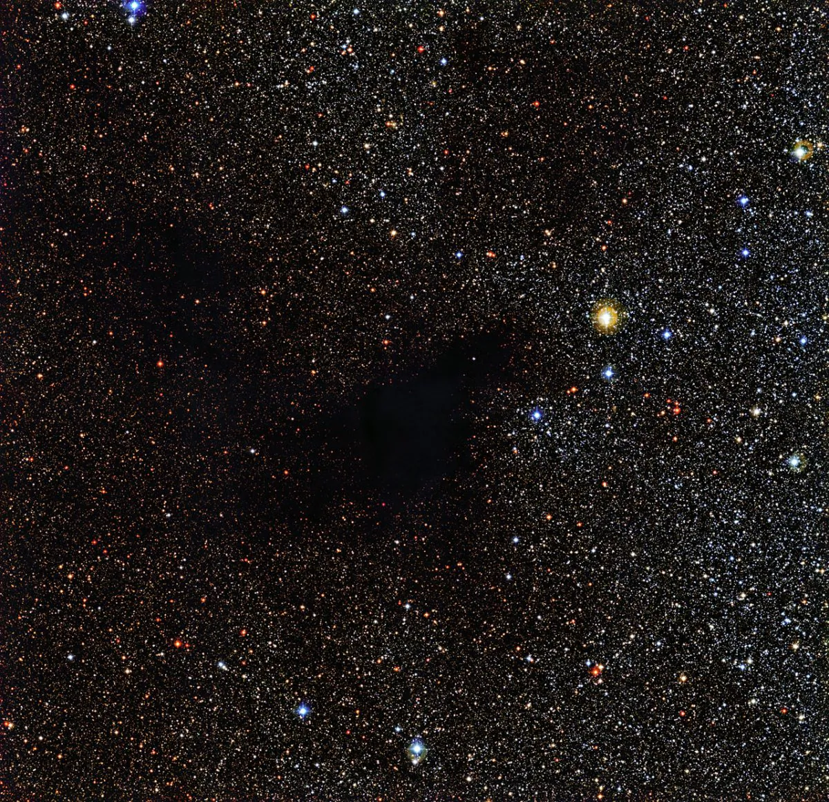 Some of the stars appear to be missing in this intriguing new ESO image. But the black gap in this glitteringly beautiful starfield is not really a gap, but rather a region of space clogged with gas and dust. This dark cloud is called LDN 483 — for Lynds Dark Nebula 483. Such clouds are the birthplaces of future stars. The Wide Field Imager, an instrument mounted on the MPG/ESO 2.2-metre telescope at ESO's La Silla Observatory in Chile, captured this image of LDN 483 and its surroundings. (ESO)