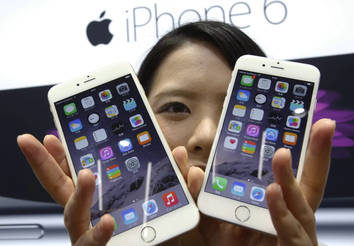 In this Sept. 19, 2014 file photo, a customer shows off the new Apple iPhone 6 and 6 Plus. (AP Photo/Shizuo Kambayashi, File)