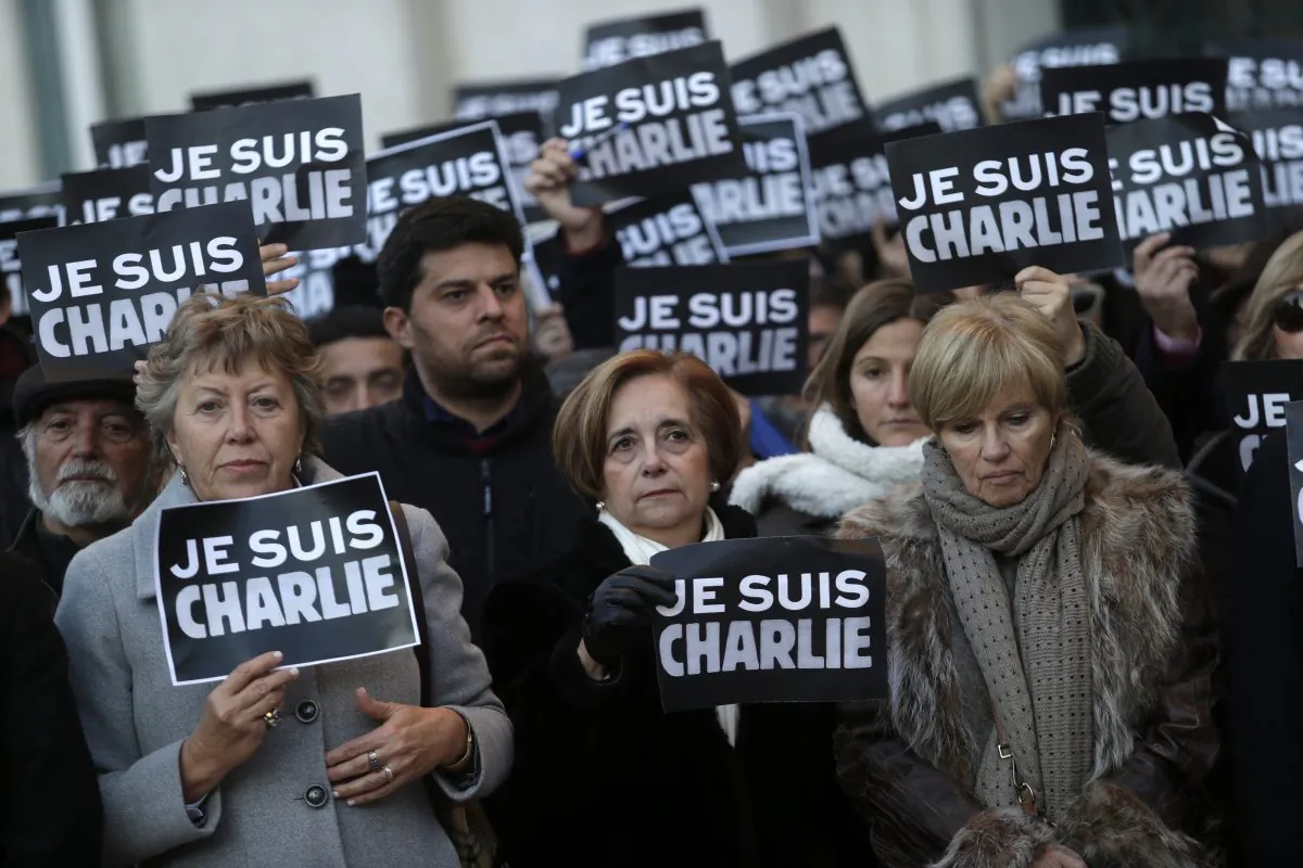 People holding paper with a slogan that reads in French: "I am Charlie" observe a minute of silence outside the Lisbon's City Hall, in honor of the people killed during the attack by gunmen at the French newspaper Charlie Hebdo's offices in Paris, in Lisbon, Thursday, Jan. 8, 2015. From Berlin to Bangkok, tens of thousands took a stand Thursday against living in fear, as rallies defended the freedom of expression and honored the victims of a Paris newspaper attack. (AP Photo/Francisco Seco)