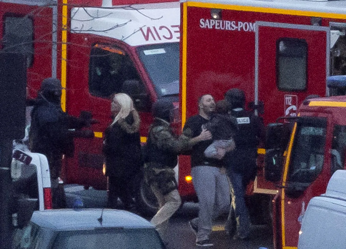 ALTERNATE CROP OF XPDA123 - A security officer directs released hostages after they stormed a kosher market to end a hostage situation, Paris, Friday, Jan. 9, 2015. Explosions and gunshots were heard as police forces stormed a kosher grocery in Paris where a gunman was holding at least five people hostage. (AP Photo/Michel Euler)