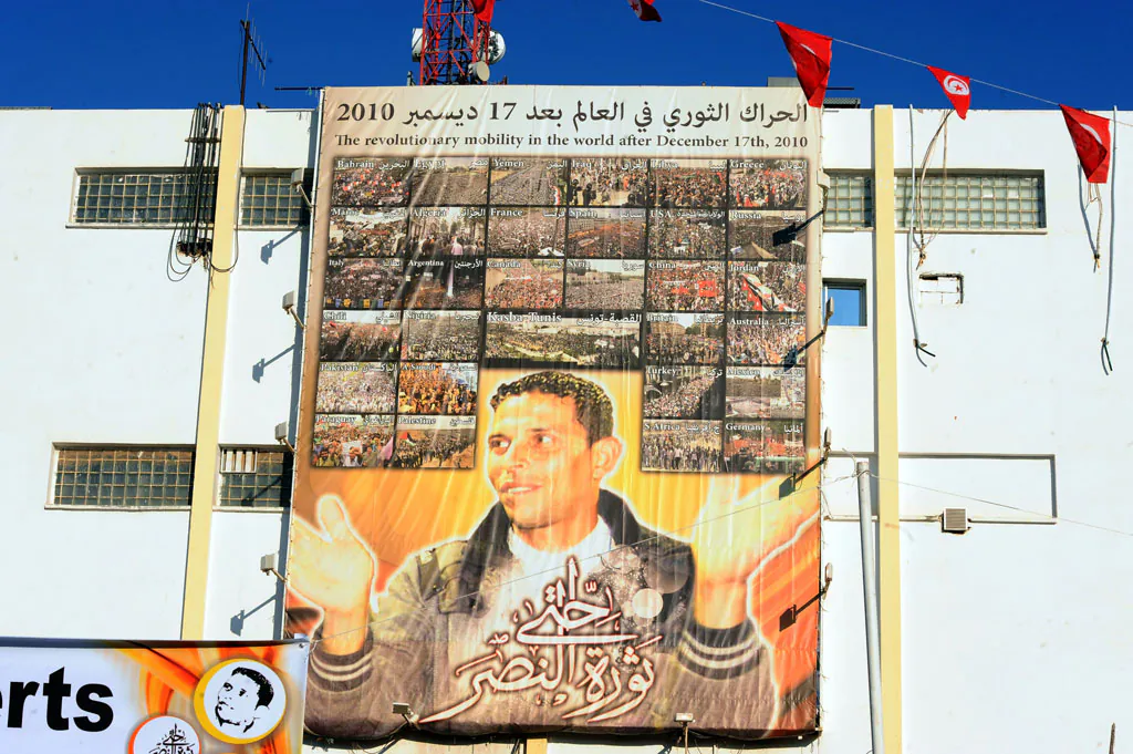 A giant portrait of Tunisian protestor Mohamed Bouazizi hangs on the wall in the central town of Sidi Bouzid on Dec. 17, 2013, as they celebrate the 3rd anniversary of the start of the revolution, the first of the Arab Spring uprisings, triggered by the self-immolation of Bouazizi, the vegetable vendor harassed by poverty and police atrocity. (Fethi Belaid/AFP/Getty Images)