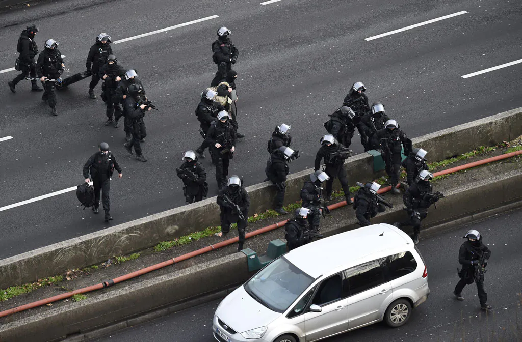 Members of the French police special force RAID walk on the 'peripherique' (circular road) in Porte de Vincennes, eastern Paris, on Jan. 9, 2015, before taking their positions after at least one person was injured when a gunman opened fire at a kosher grocery store on Jan. 9 and took at least five people hostage, sources told AFP. The attacker was suspected of being the same gunman who killed a policewoman in a shooting in Montrouge in southern Paris on Jan. 8. (Eric Feferberg/AFP/Getty Images)