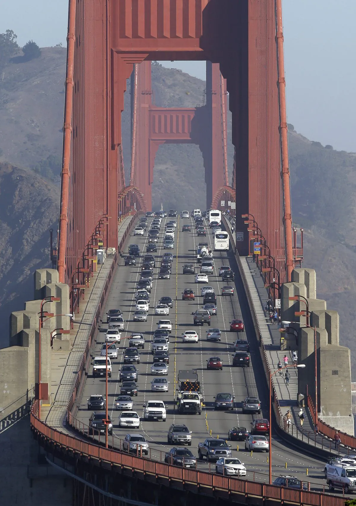 FILE - In this Thursday, Sept. 19, 2013 file photo, Golden Gate Bridge workers shift traffic lanes during the end of the morning commute in San Francisco. The Golden Gate Bridge will close to vehicles for 52 hours starting early Saturday morning, Jan. 10, 2014 to install a steel and concrete moveable median barrier that will help make the iconic bridge safer to commuters. (AP Photo/Eric Risberg)