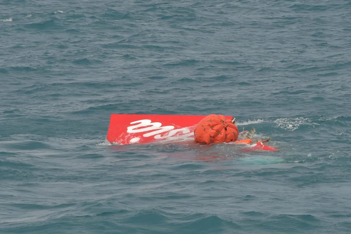 Portion of the tail of AirAsia Flight 8501 floats on the water as Indonesian navy divers conduct search operations for the black boxes of the crashed plane in the Java Sea, Indonesia, Saturday, Jan. 10, 2015. Investigators searching for black boxes in the crashed AirAsia plane lifted the tail portion out of the Java Sea on Saturday, two weeks ago after it went down, killing all 162 people on board. (AP Photo/Adek Berry, Pool)