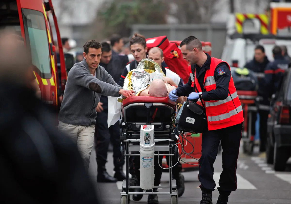 An injured person is transported to an ambulance after a shooting at the French satirical newspaper Charlie Hebdo's office in Paris, France, Jan. 7, 2015. (AP Photo/Thibault Camus)