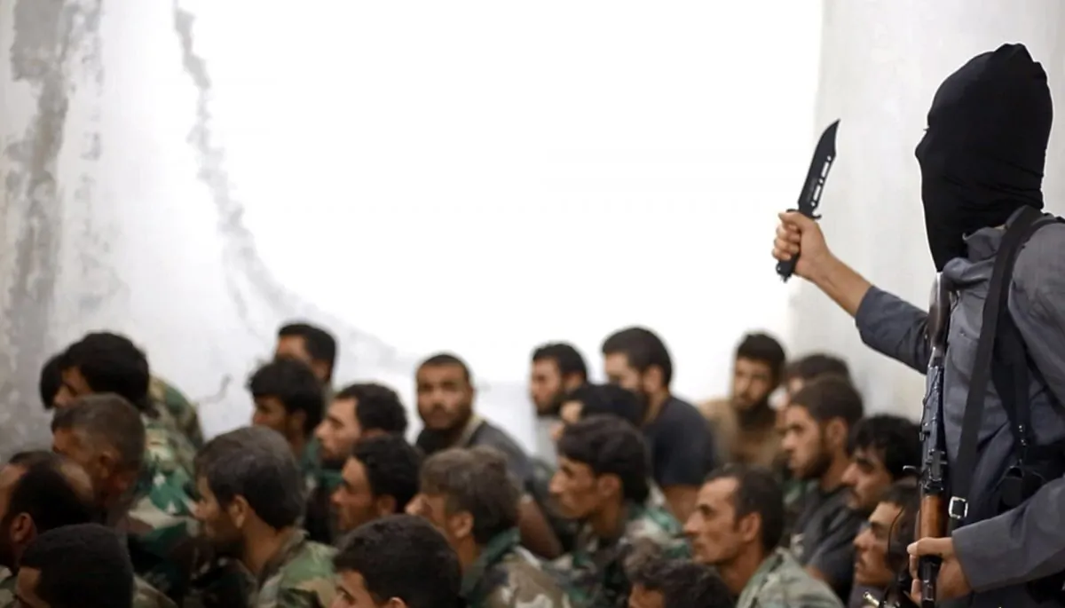 A fighter from the Islamic State group, armed with a knife and an automatic weapon, next to captured Syrian army soldiers and officers, following the battle for the Tabqa air base in Raqqa, Syria, on Aug. 27, 2014. The militant chatter spread like wildfire. Within minutes of news breaking about the deadly terror attack on a Paris newspaper, supporters of the Islamic State group extolled the suspects in the massacre as "lions of the caliphate" and praised the killings on social media. (AP Photo/Raqqa Media Center of the Islamic State group)