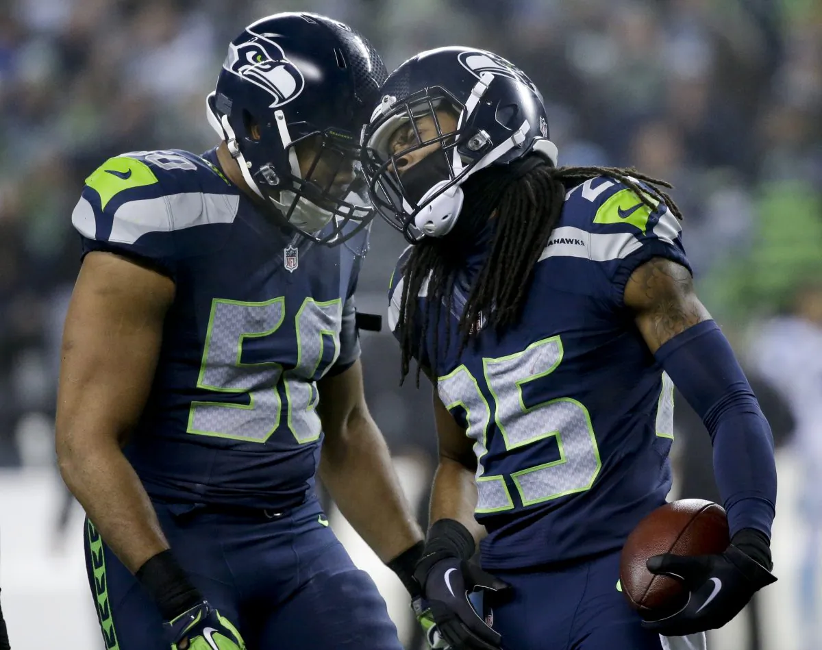 Seattle Seahawks cornerback Richard Sherman, right, celebrates after intercepting a pass by Carolina Panthers quarterback Cam Newton with outside linebacker K.J. Wright (50) during the first half of an NFL divisional playoff football game in Seattle, Saturday, Jan. 10, 2015. (AP Photo/Elaine Thompson)