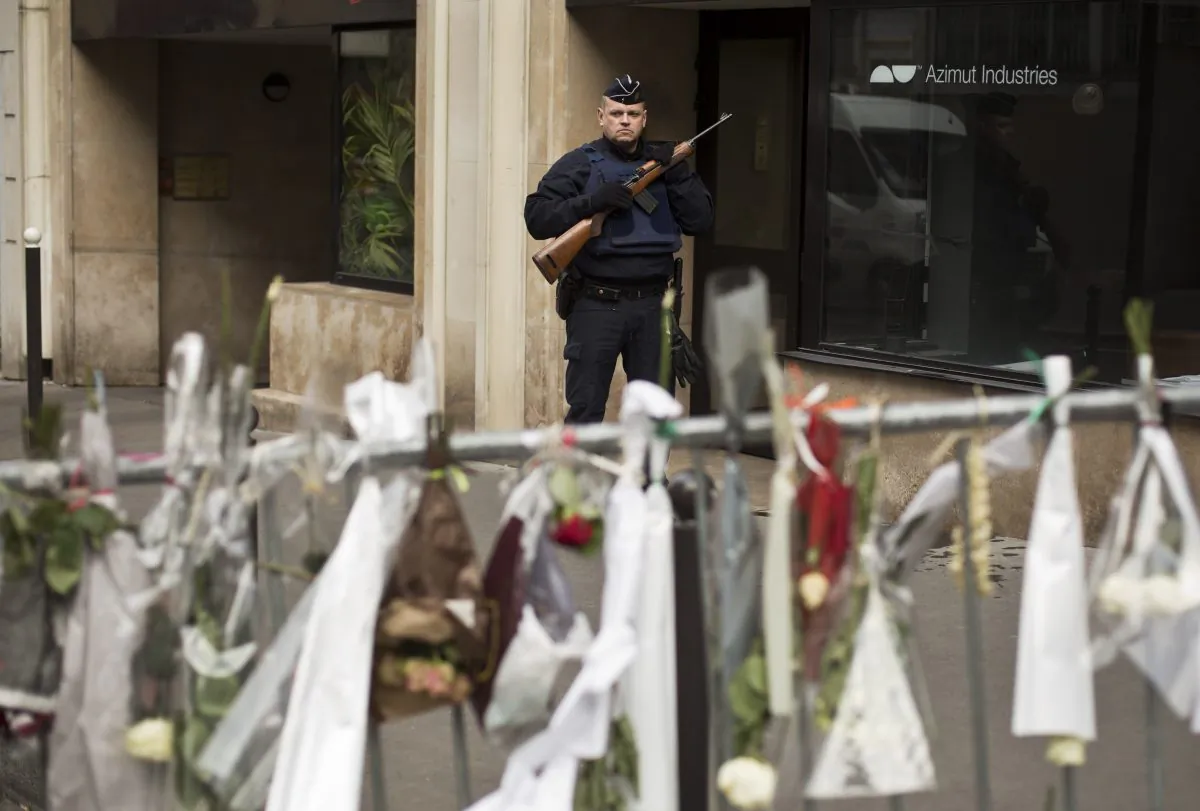 A French police officer stands guard on a road leading to the offices of French satirical newspaper Charlie Hebdo in Paris, Saturday, Jan. 10, 2015. France's government urged the nation to remain vigilant Saturday, as thousands of security forces try to thwart new attacks and hunt down a suspected accomplice in a rampage by terrorists linked to al-Qaida in Yemen that scarred the nation and left 20 dead. (AP Photo/David Azia)