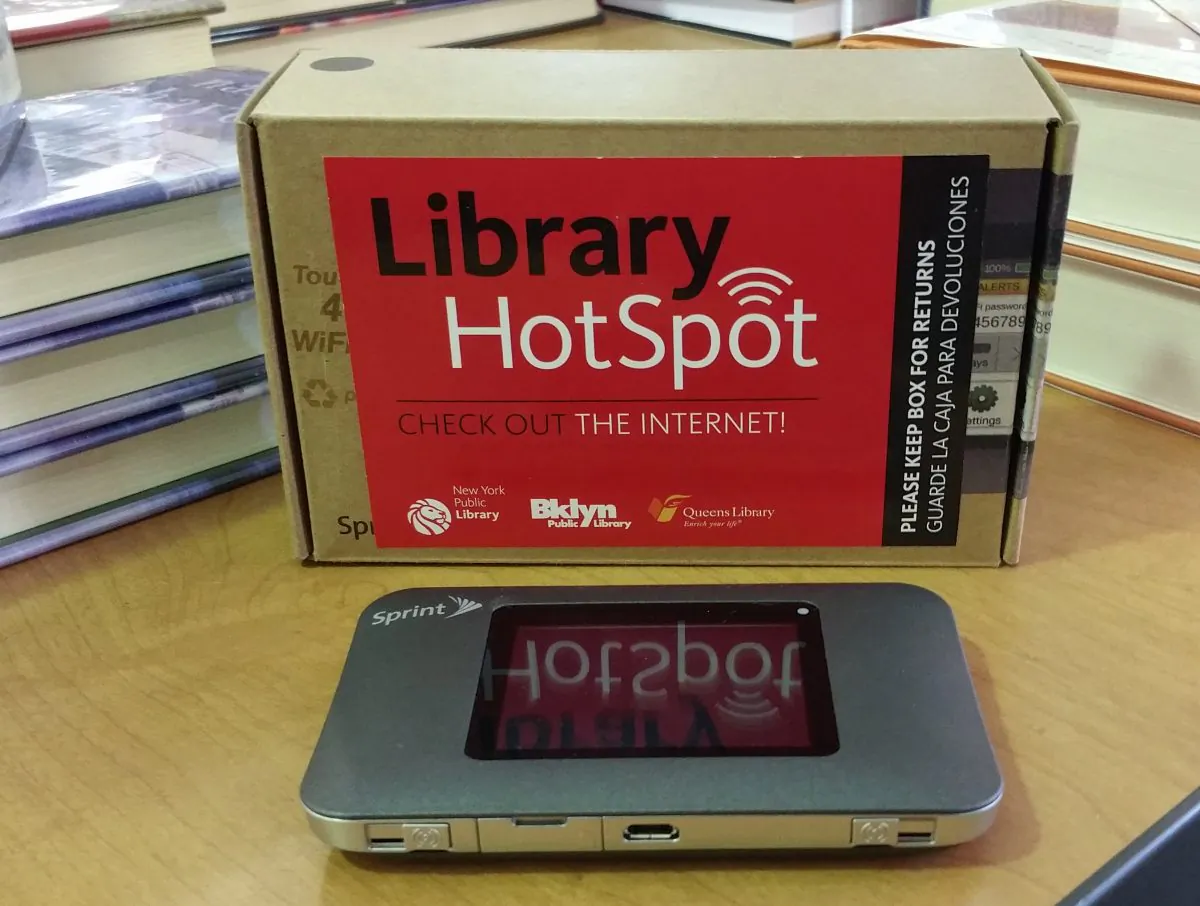 A mobile wireless Internet hotspot lay on a desk among piles of books at the Free Public Library in New York on Jan. 10, 2015. The New York Public Library is launching the nation’s largest Internet lending program, which provides 10,000 of these hot spots free for one year to some of the city's poorest residents. (AP Photo/Verena Dobnik)