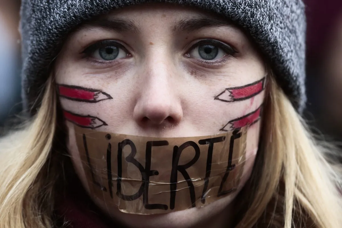 A woman has taped her mouth  displaying the word Freedom  on the tape,  as she gathers with several thousand people in solidarity with victims of two terrorist attacks in Paris, Jan. 11, 2015. (AP Photo/Markus Schreiber)