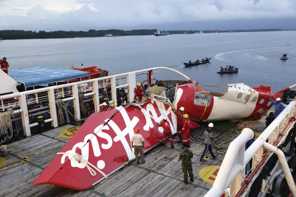 Crew members of Crest Onyx ship prepare to unload parts of AirAsia Flight 8501 from a ship at Kumai port in Pangkalan Bun,Sunday, Jan.11, 2015. A day after the tail of the crashed AirAsia plane was fished out of the Java Sea, the search for the missing black boxes intensified Sunday with more pings heard. (AP Photo/Achmad Ibrahim)