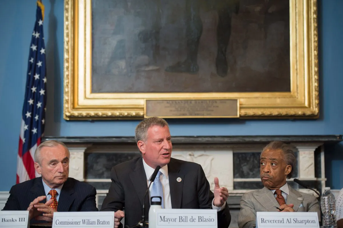 New York Mayor Bill de Blasio (C) is seated between New York City Police Commissioner William Bratton (L) and the Rev. Al Sharpton during a round table discussion convened to ease tensions over the death of Eric Garner, a black man who died from a police choke hold while being arrested. De Blasio has been unable to heal the deepening rift with the NYPD and erase the perception that he is not supporting the police. (AP Photo/New York City Mayoral Photography Office, Bob Bennett)