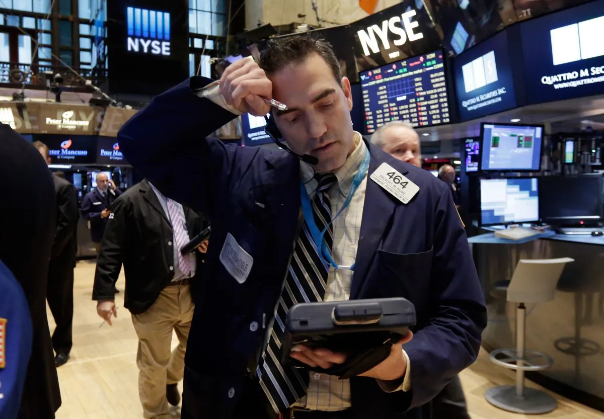 Trader Gregory Rowe wipes his forehead as he works on the floor of the New York Stock Exchange Wednesday, Jan. 14, 2015. (AP Photo/Richard Drew)