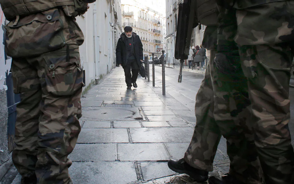 Soldiers patrol a street in Paris, Wednesday, Jan. 14, 2015. France ordered 10,000 troops into the streets Monday to protect sensitive sites — nearly half of them to guard Jewish schools — as it hunted for accomplices to the Islamic militants who left 17 people dead as they terrorized the nation. (AP Photo/Christophe Ena)