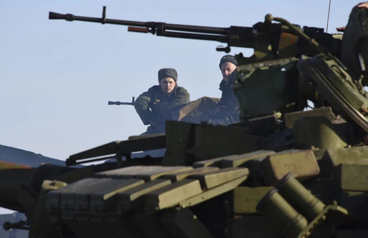 In this Wednesday, Jan. 14, 2015 photo Russian-backed separatist sit on top a tank at the check-point north of Luhansk, Eastern Ukraine. An attack on a passenger bus in eastern Ukraine killed 12 people Tuesday, likely dealing the final blow to hopes that a short-lived and shaky cease-fire could take hold. (AP Photo/ Mstyslav Chernov)