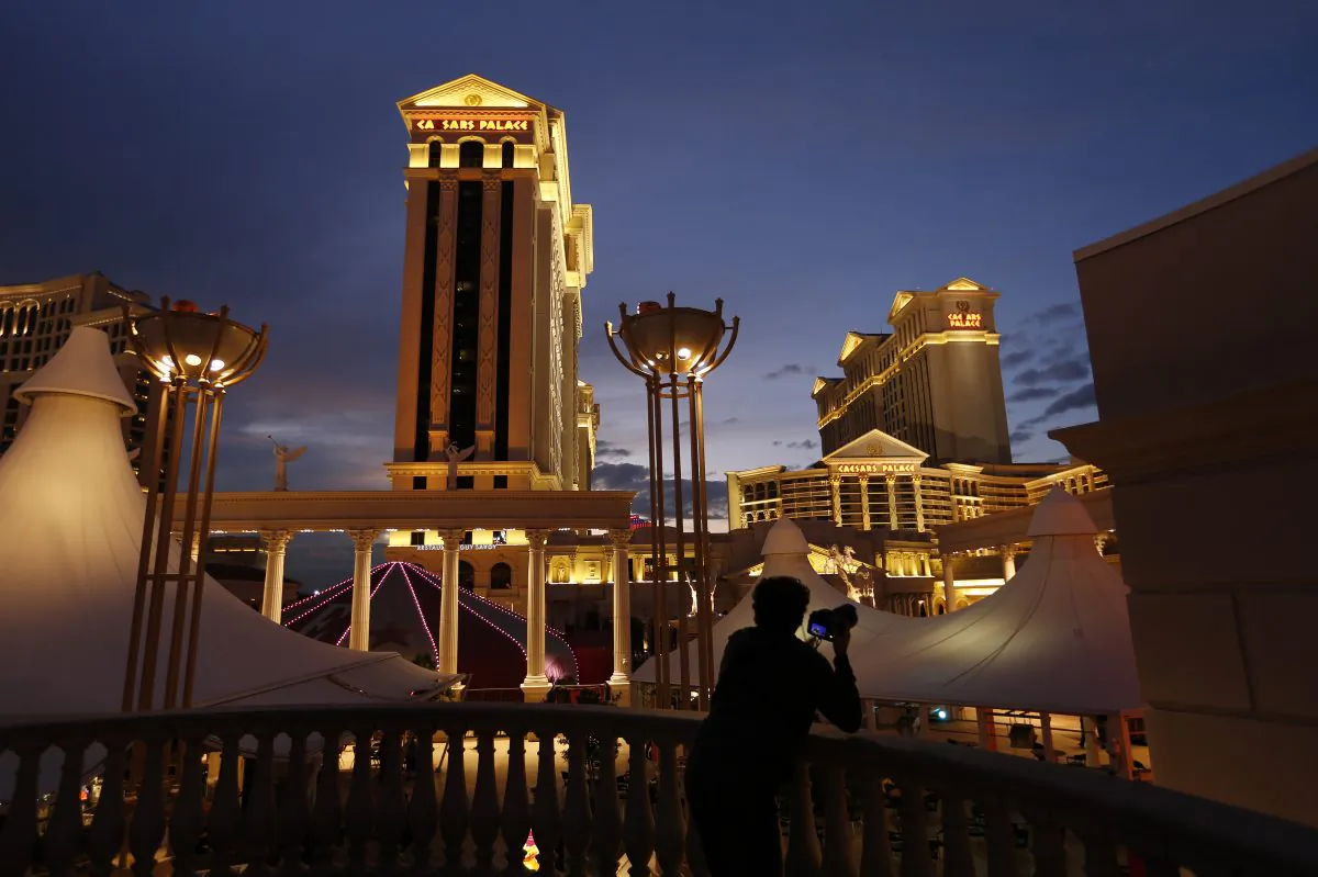 A man takes pictures of Caesars Palace hotel and casino, in Las Vegas, on Jan. 12, 2015. A cash-strapped division of casino giant Caesars Entertainment Corp. said early Thursday Jan. 15, 2015 that it filed for bankruptcy protection in Chicago, hoping the court agrees to its plan to get out from under $18.4 billion of debt. (AP Photo/John Locher)